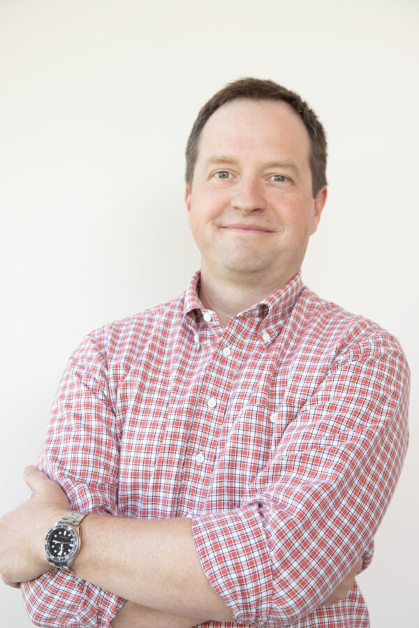 A confident, smiling middle-aged professional man dons a vibrant patterned collared button-down.
