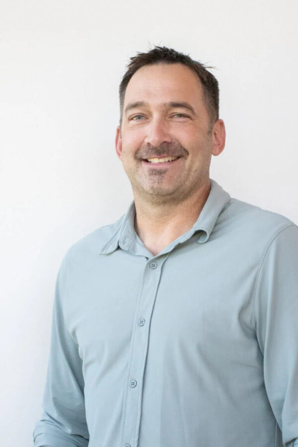 Smiling remodeling expert wears sleek light-blue collared shirt.
