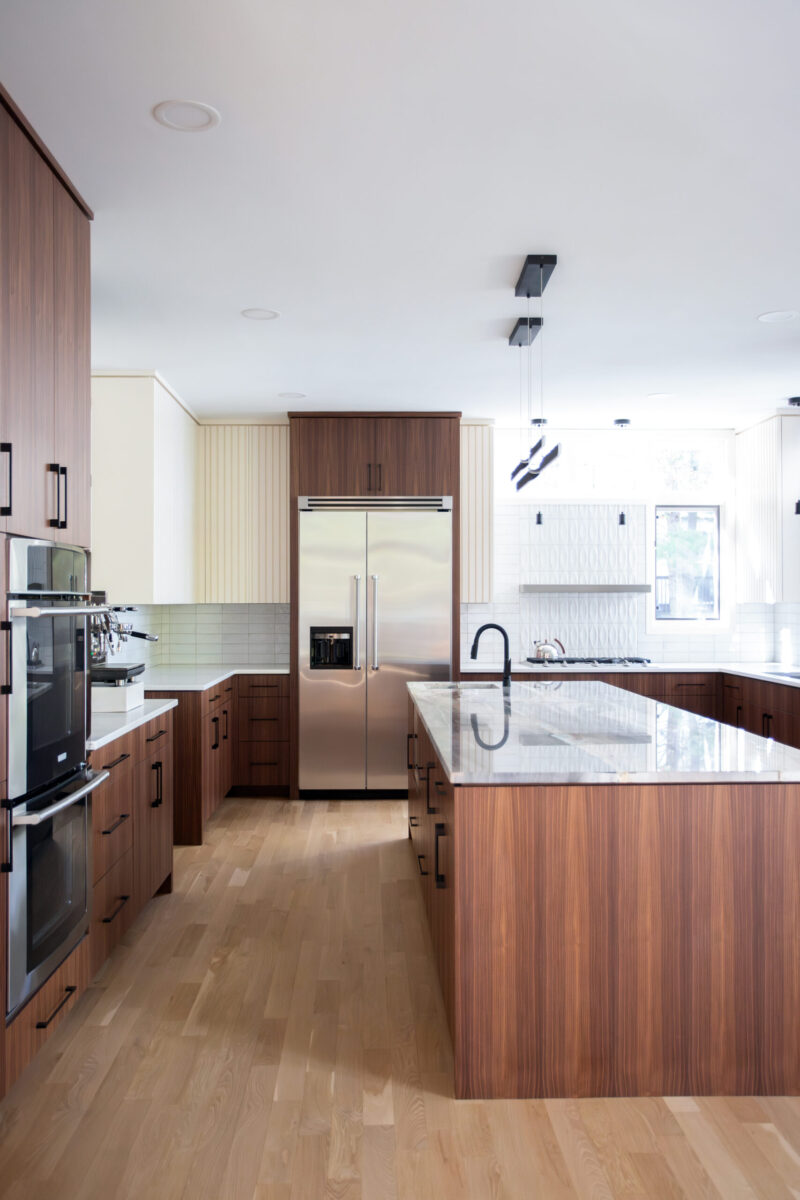 Contemporary Twin Cities kitchen remodel features rich cabinetry, white countertops, steel appliances, and wood floors.