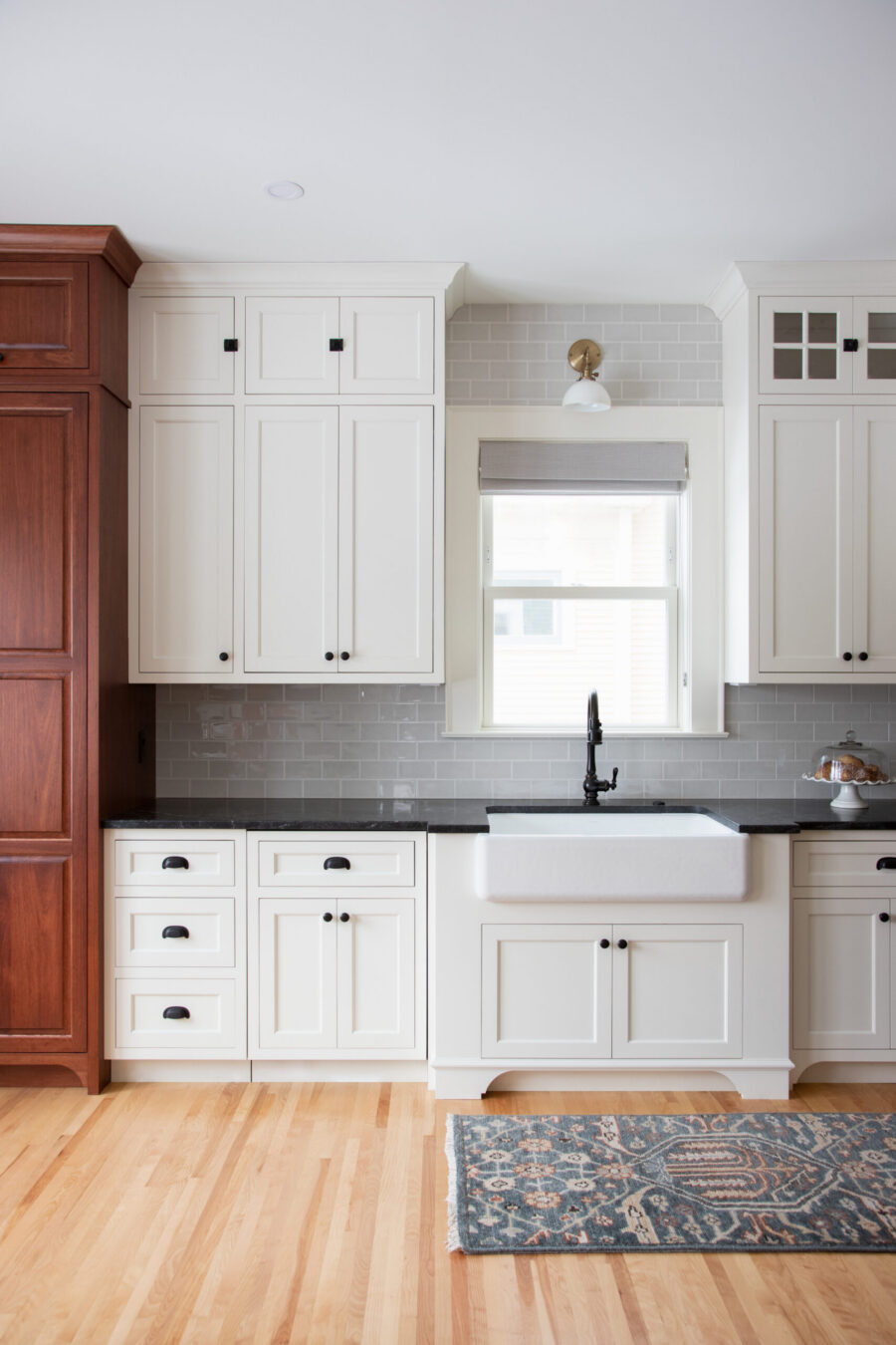 White-shaker-cabinetry frames farmhouse-apron sink beneath brass-sconce lighting, Twin Cities