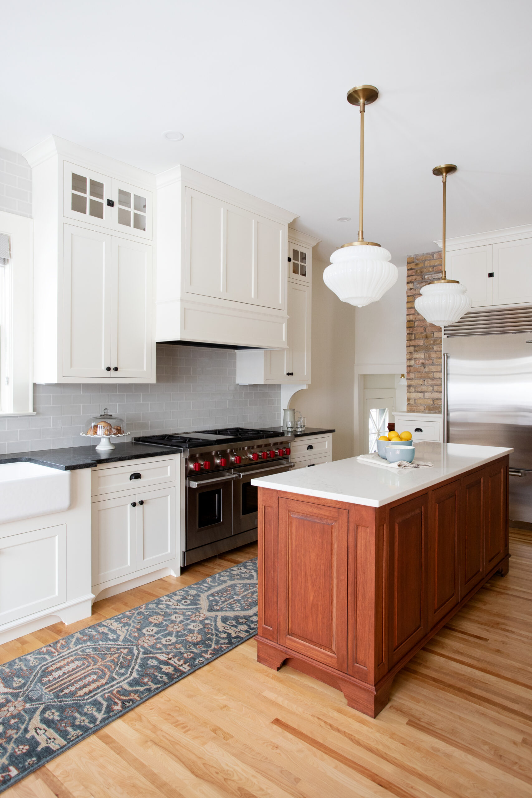 Stone island anchors white-cabinetry, brick-accent wall, brass-pendant lighting kitchen-remodel