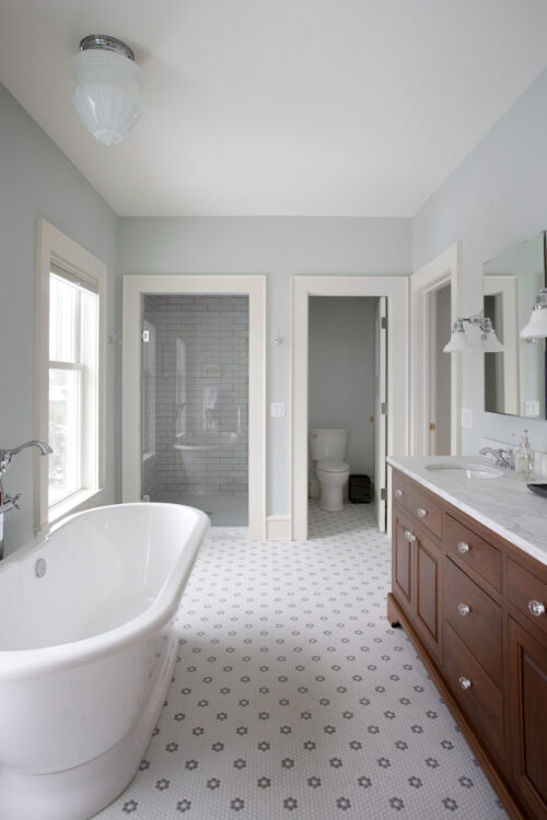 Renovated Twin Cities bathroom includes freestanding tub, glass shower, dark vanity.