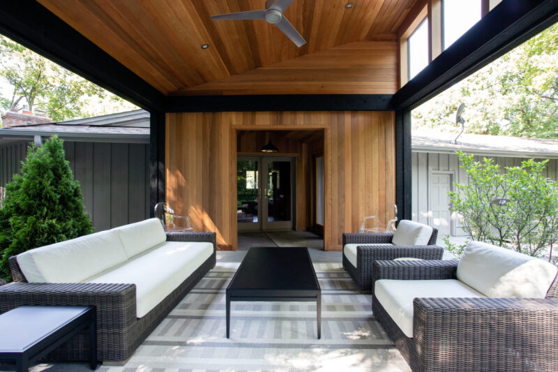 Exquisite timbered outdoor living area features dark woven seating, accentuating modern design build elements.