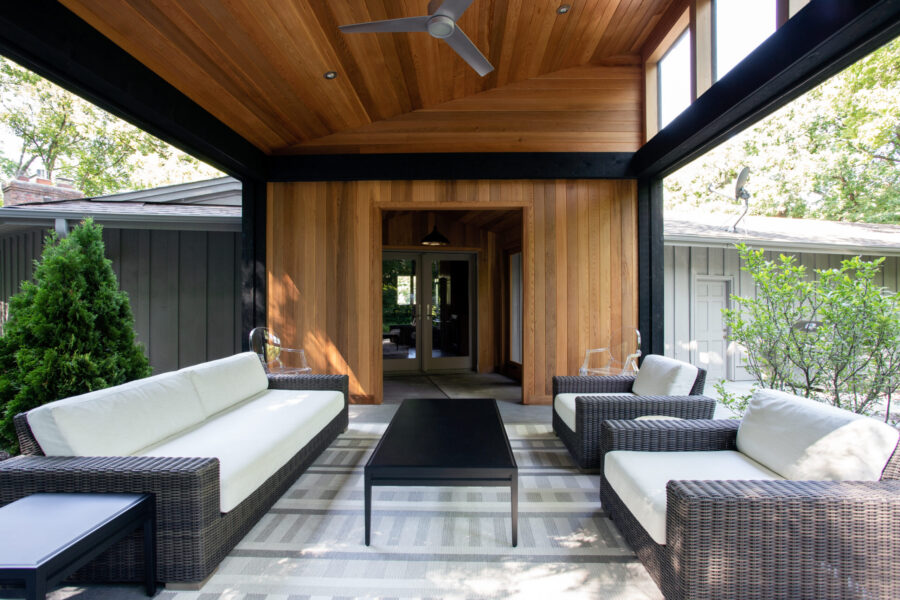 Exquisite timbered outdoor living area features dark woven seating, accentuating modern design build elements.