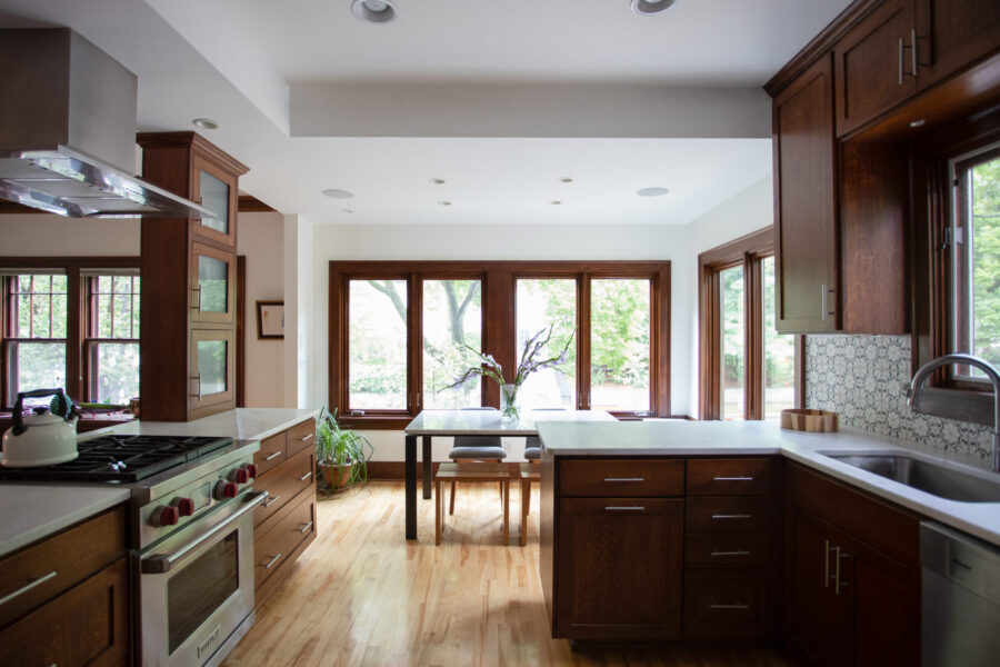 Modern kitchen remodel boasts dark cabinets, white counters, wood floors, and bright windows.