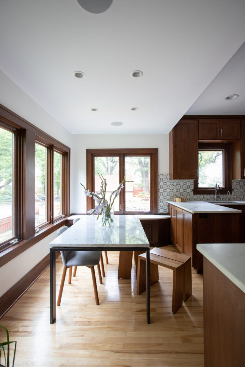 Twin Cities kitchen remodel combines rich wood cabinets, white marble counters, light flooring, and ample window lighting.