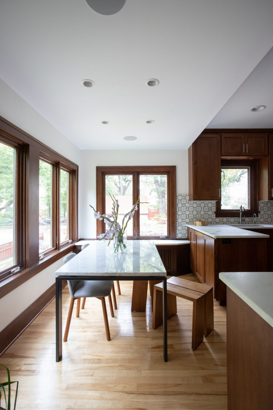 Twin Cities kitchen remodel combines rich wood cabinets, white marble counters, light flooring, and ample window lighting.