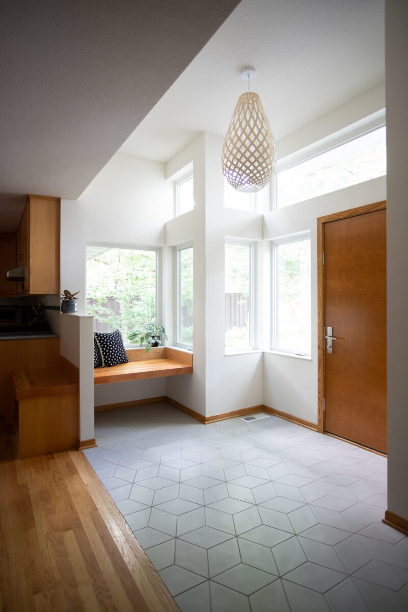 A bright Twin Cities home renovation features a wood kitchen, built-in window seat, and geometric floor tiles.