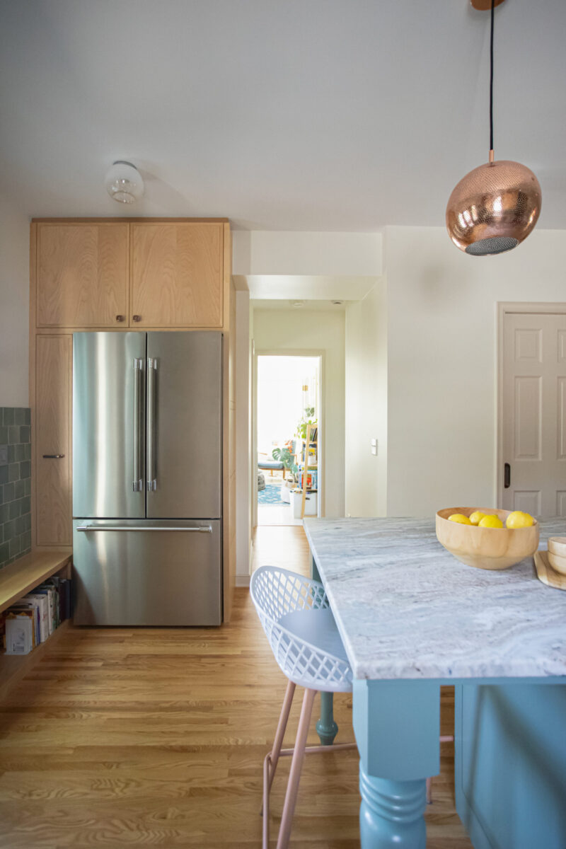 Kitchen remodel blends light wood cabinetry, sleek stainless steel, blue island, marble.