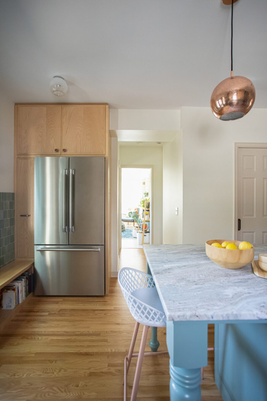 Kitchen remodel blends light wood cabinetry, sleek stainless steel, blue island, marble.