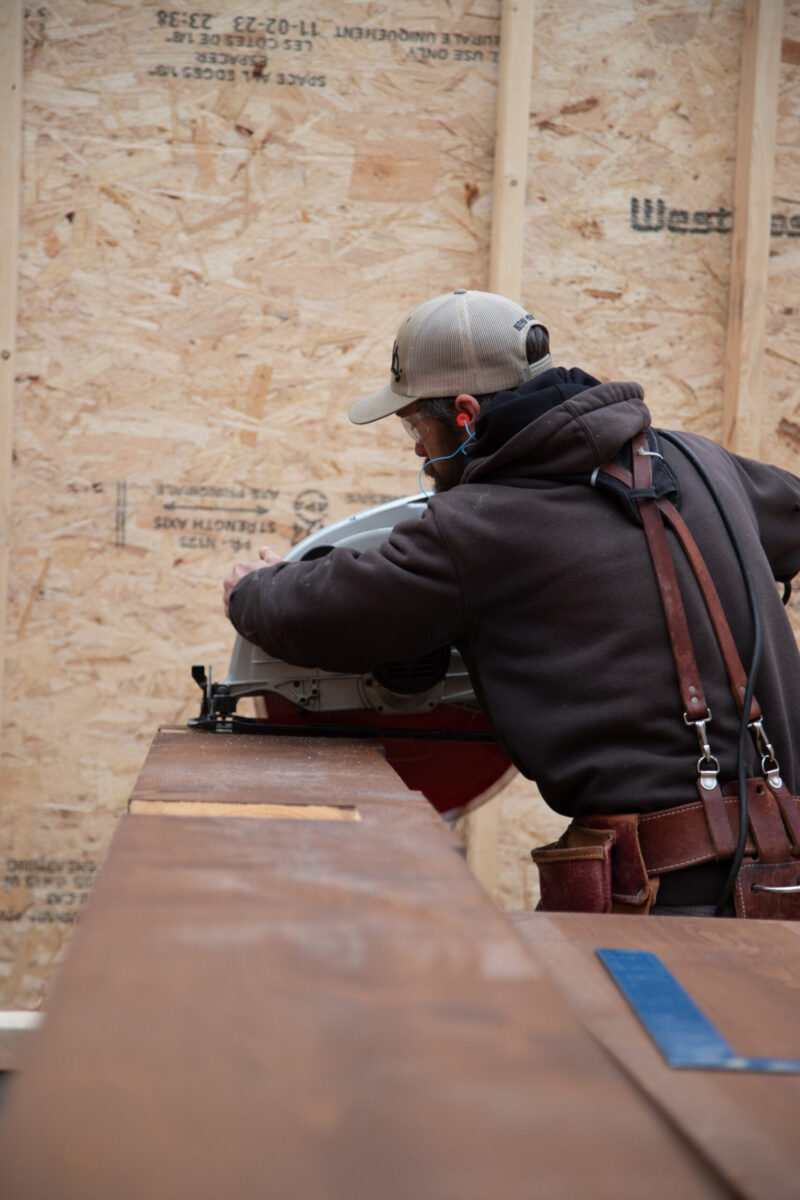 Craftsman meticulously saws rich hardwood for interior design-build renovation.
