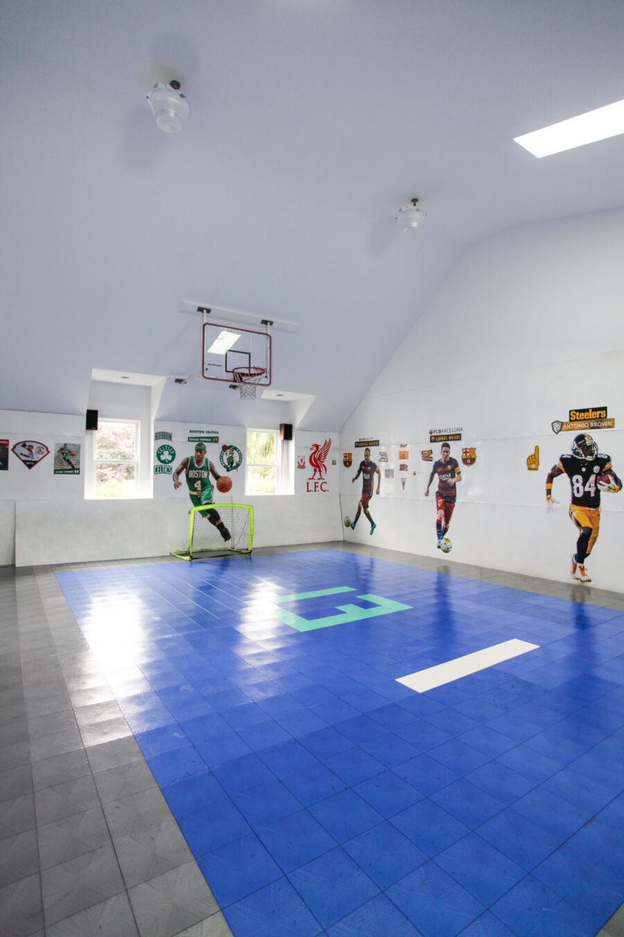 Twin Cities home renovation delivers a bright indoor sports court. Blue tile, a basketball hoop, and sports decals.