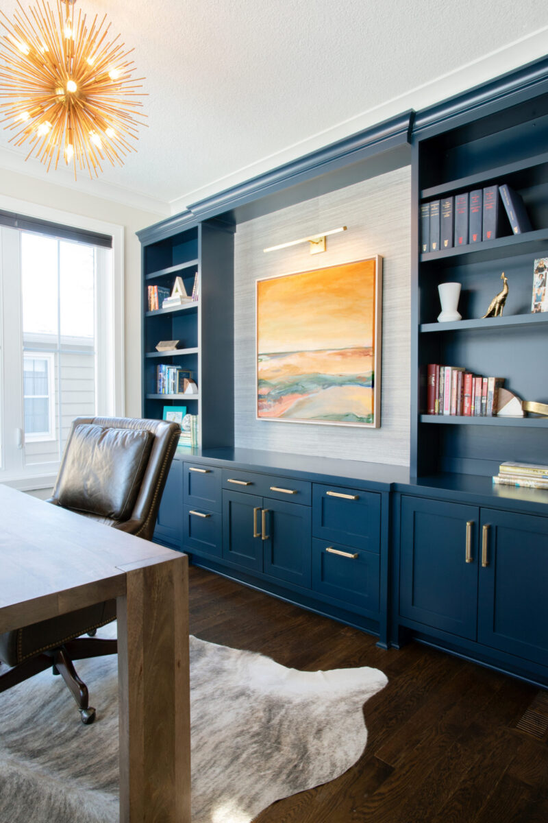 Designers renovate Twin Cities office: custom navy built-ins, desk, gold chandelier.