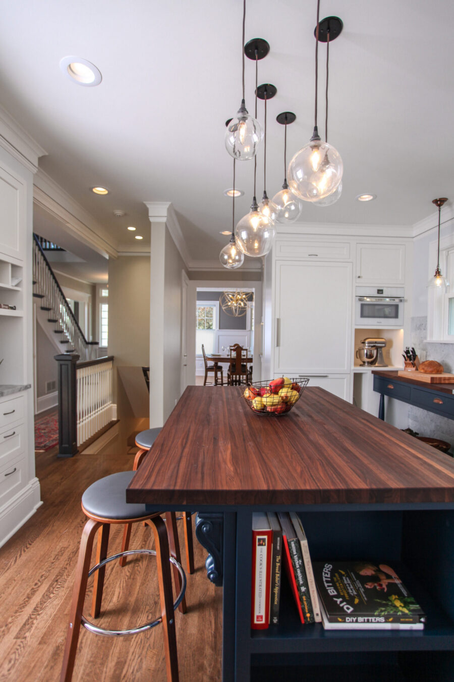 Bright Twin Cities kitchen renovation features a long dark wood island, glass pendant lights, and white cabinets.