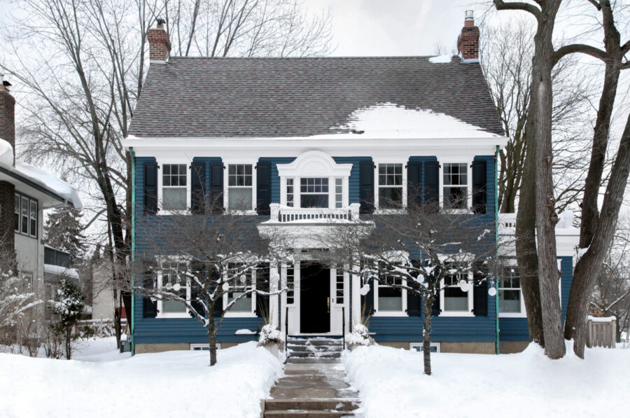 blue siding exterior remodel highlights classic home architecture with bright white trim in winter snow
