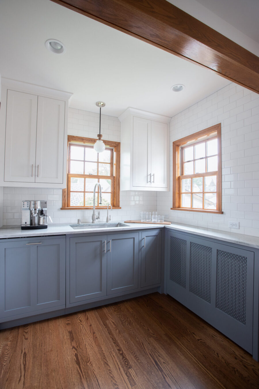 Bright Twin Cities kitchen remodel features white and gray shaker cabinets, subway tile, wood flooring, and ample natural light.