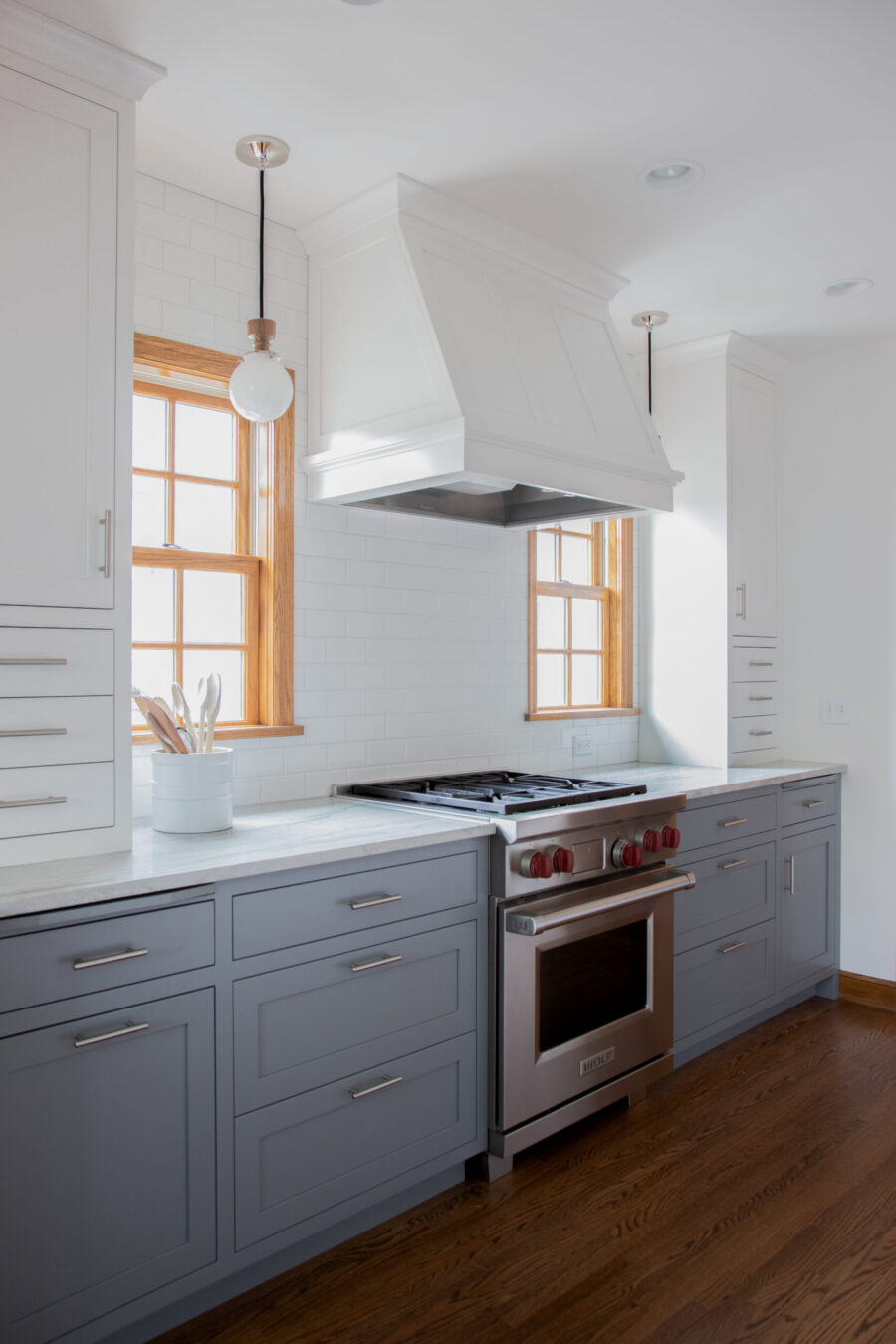 Kitchen remodel features gray-white cabinetry, subway tile, and dark wood floors.