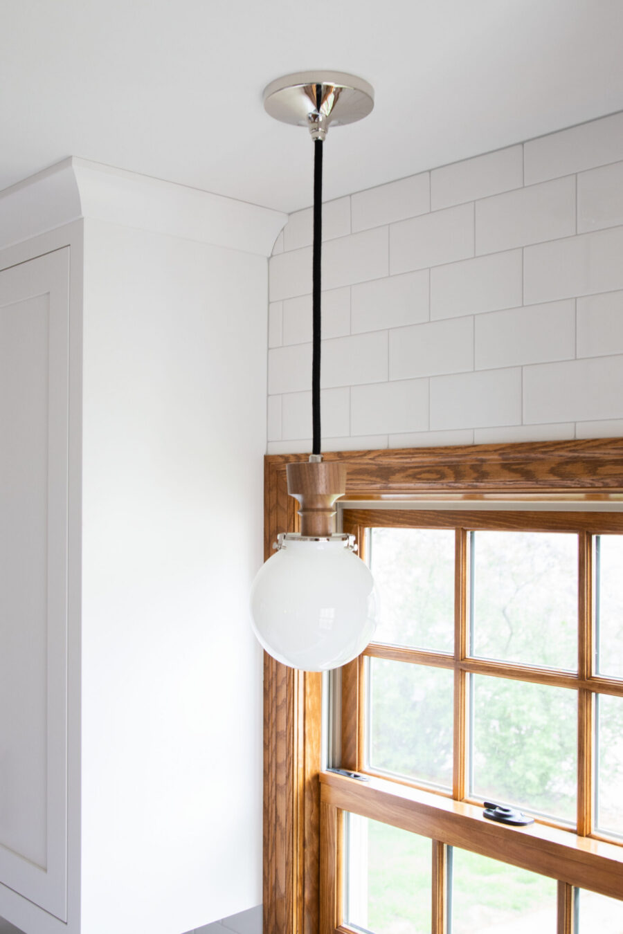 Pendant light illuminates white subway tile and a natural wood window in this Twin Cities kitchen remodel.