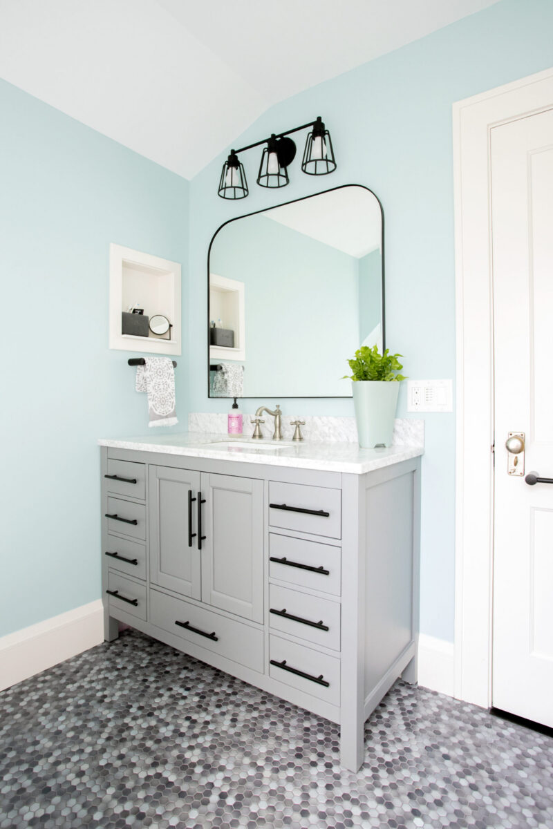 Aquamarine bathroom renovation: gray cabinetry, hexagonal flooring, black accents.