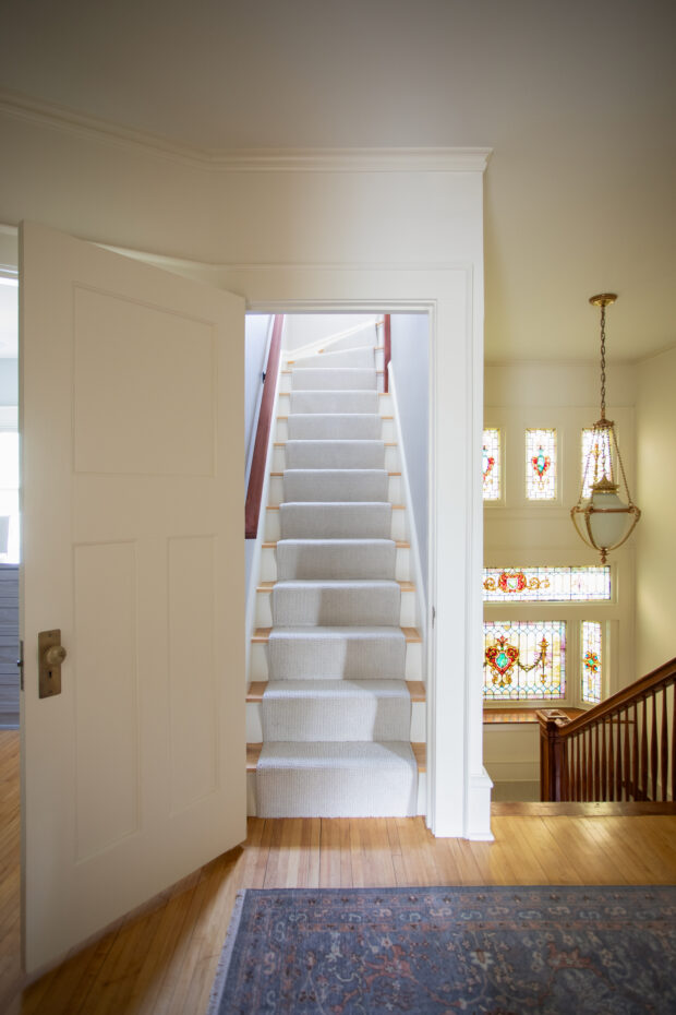 Historic interior remodel featuring restored staircase, stained glass windows, and refined craftsmanship in a Minneapolis home renovation project