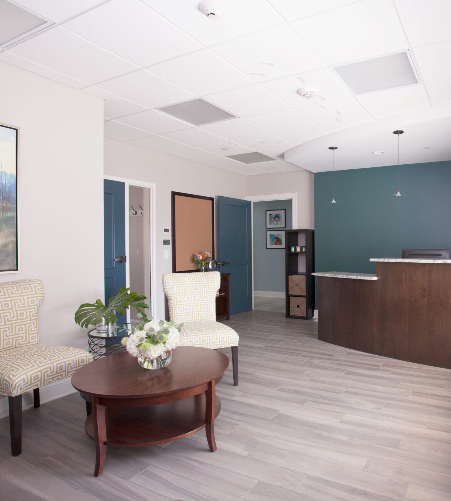 Modern medical office reception area with teal accent wall, wood reception desk, and contemporary waiting seating.