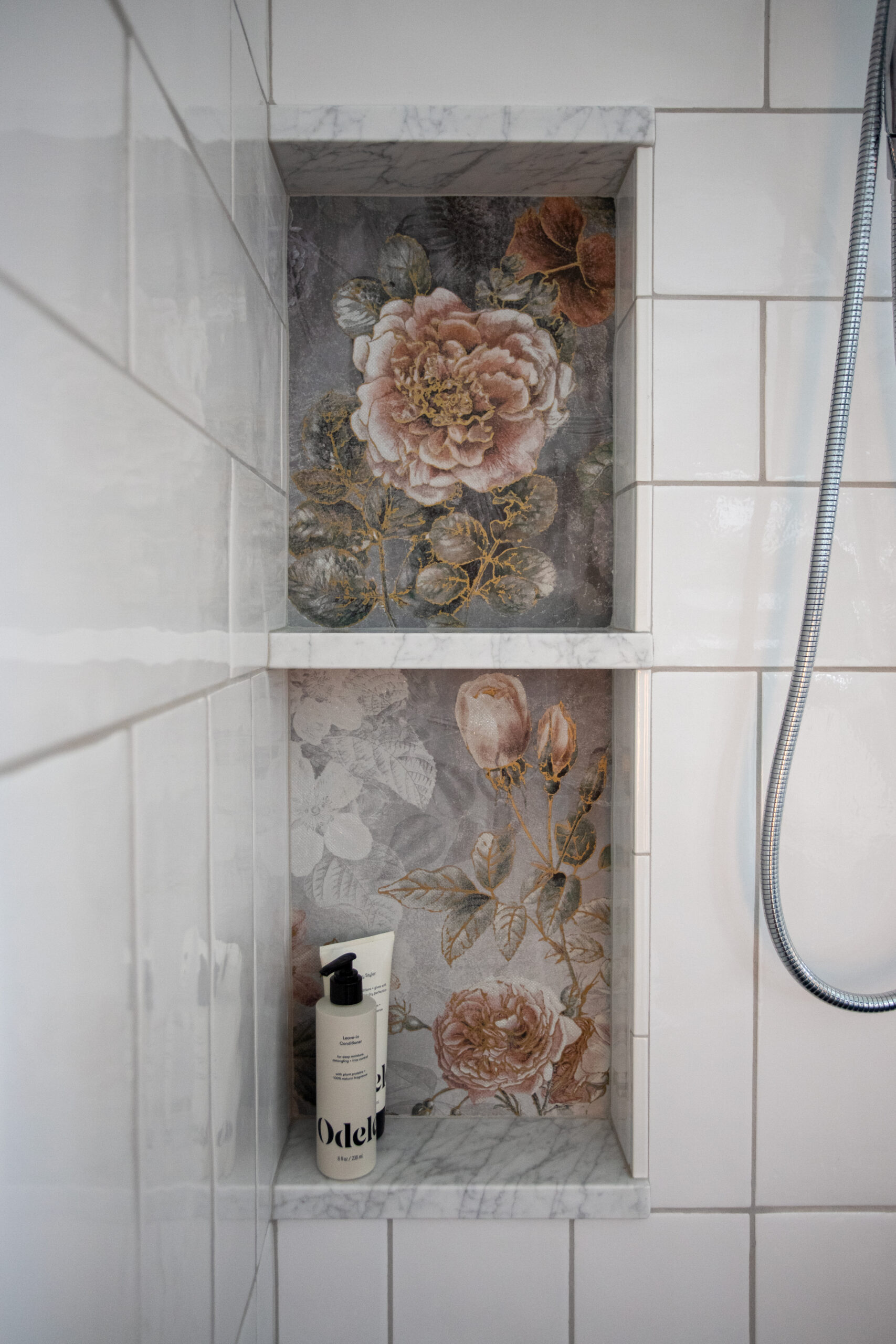 Bathroom shower niche with botanical floral wallpaper and soap dispenser on shelf