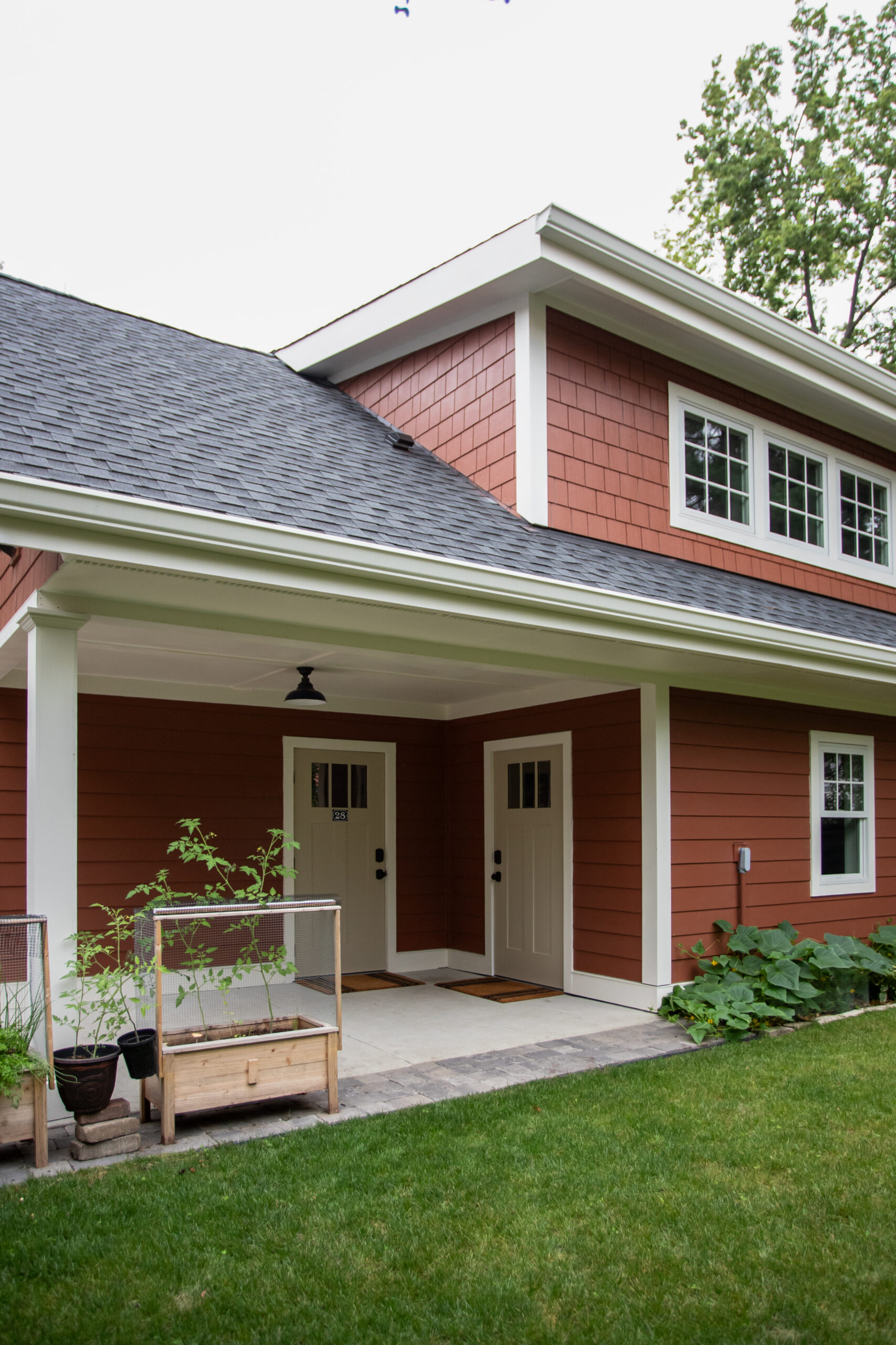 Red modern home with covered porch, white trim, and architectural design services for custom residential additions.