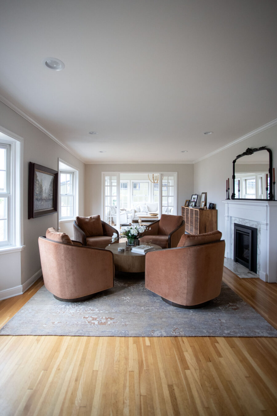 Living room with four orange-brown curved chairs arranged around a round coffee table on a patterned rug.