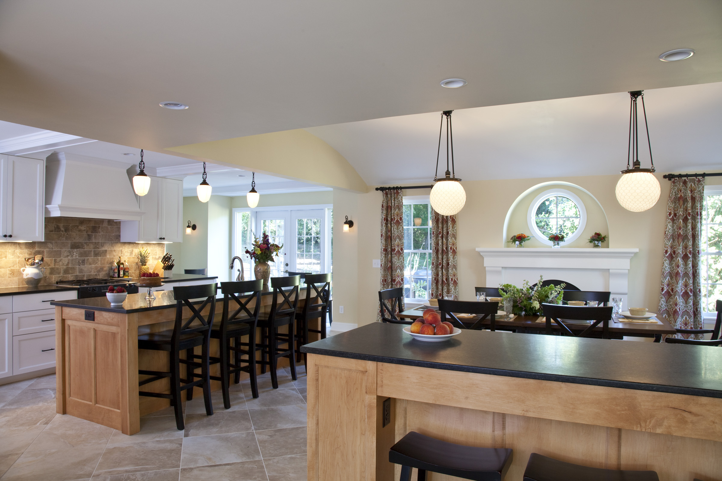 Open-concept kitchen and dining area with wood island, black countertops, pendant lighting, and fireplace designed by kitchen remodel specialists.