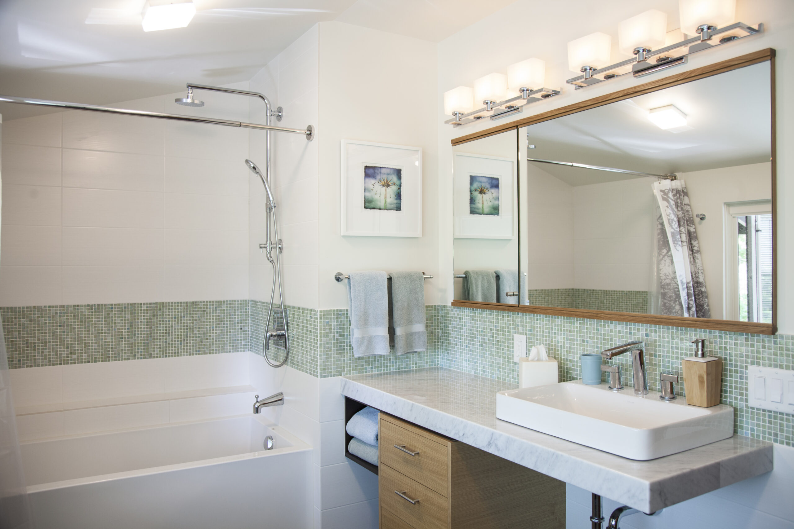 Modern bathroom with mint green tile backsplash, floating vanity, large mirror with lighting, and walk-in shower with glass enclosure.