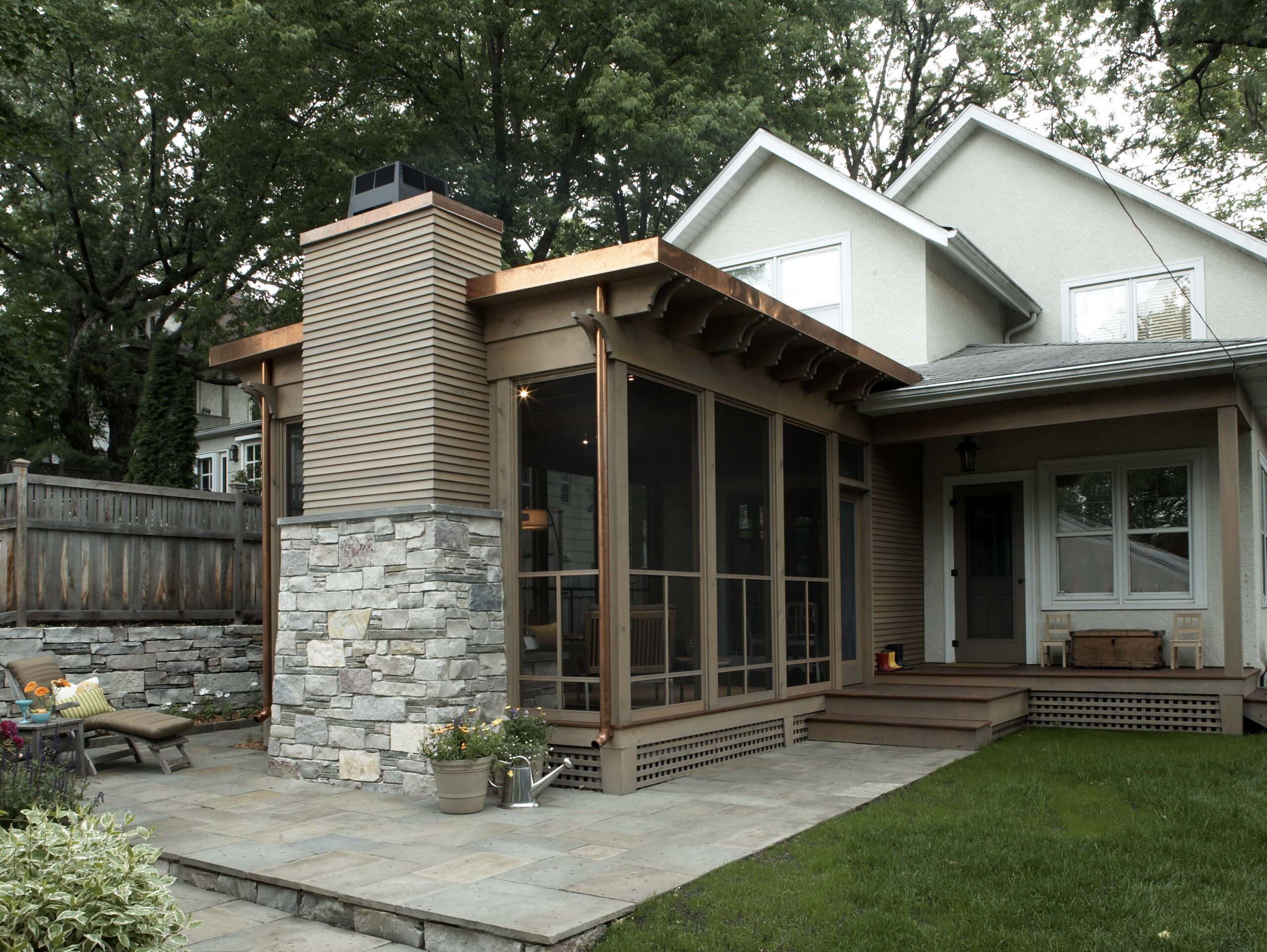 Modern home addition with stone chimney, wood framing, screened porch and patio in Minneapolis.