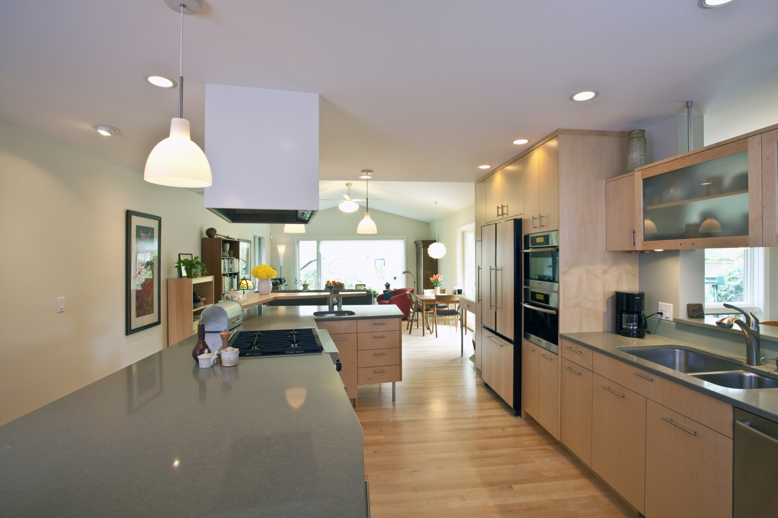 Modern kitchen remodel featuring custom cabinetry, stainless steel appliances, and gray countertops with natural wood flooring.