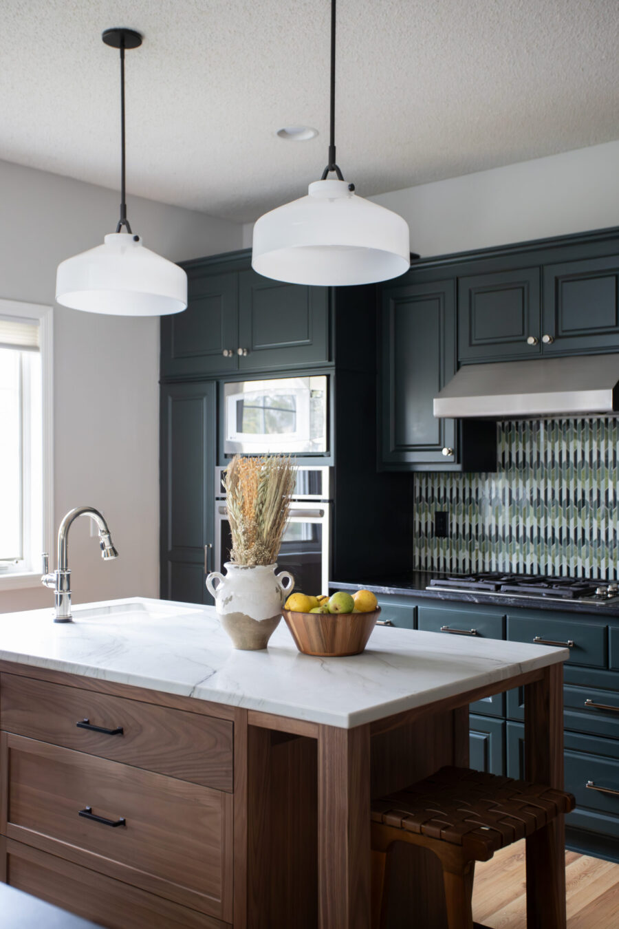 Modern kitchen with dark navy cabinets, a white marble island, and two white pendant lights overhead.